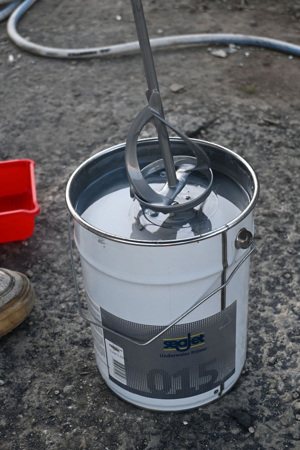 Mixing a tin of two-part coating with a drill paddle